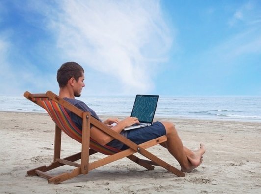 a man sitting in a beach chair on his laptop