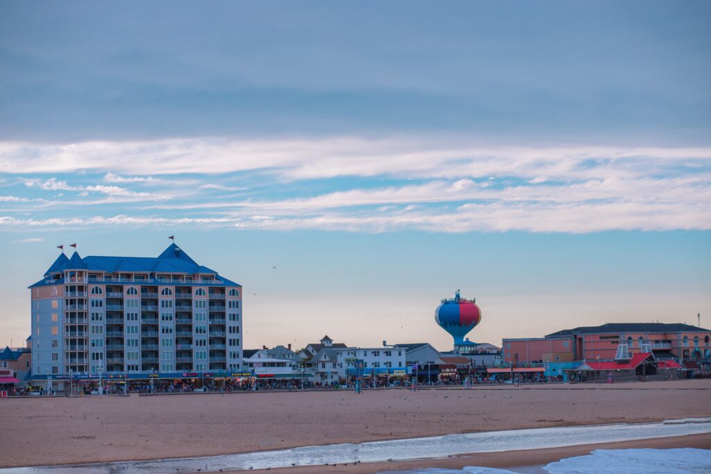 a beach with buildings and hot air balloons in the sky