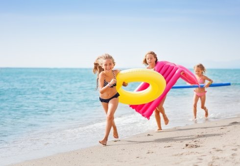 three girls are playing on the beach with an inflatable object