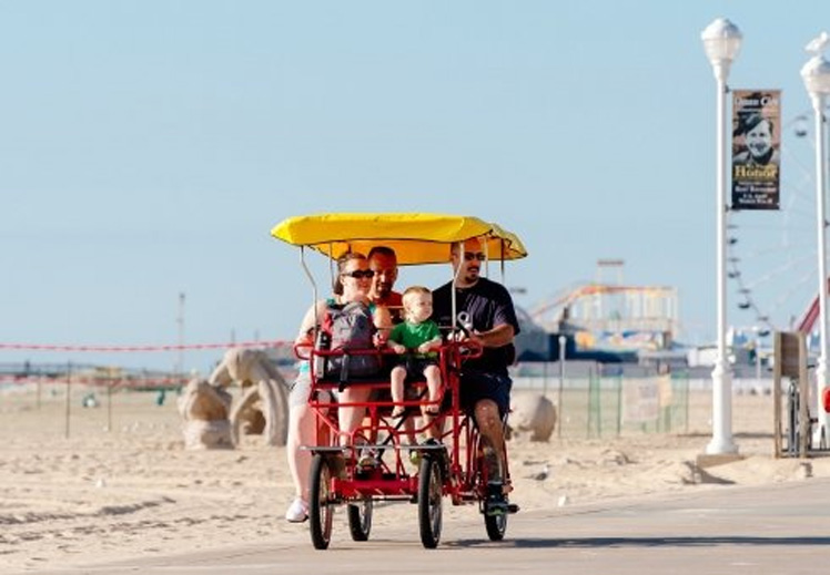 a man and two children riding in a red cart on the beach