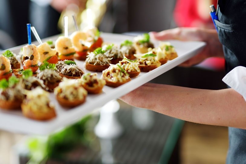 a person holding a tray with appetizers on it