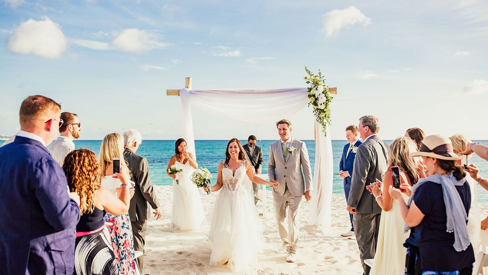 a bride and groom walking down the beach